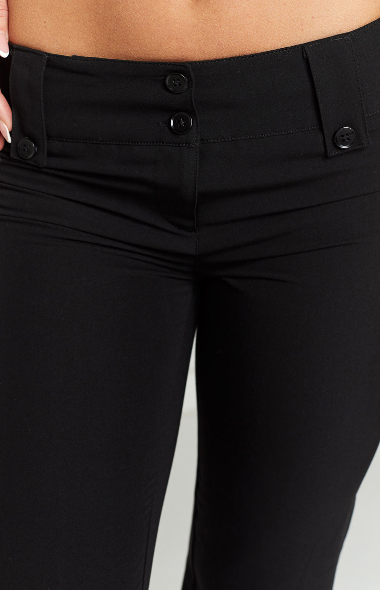 Close-up of the low-rise waistband of black pants, showing a two-button front closure and decorative button tabs