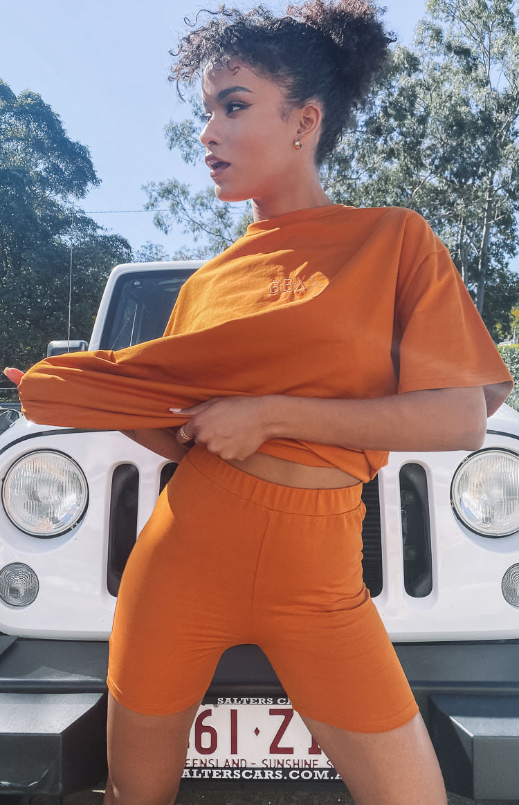 Tan high-waisted fitted jersey shorts with an elastic waistband, mid-thigh length