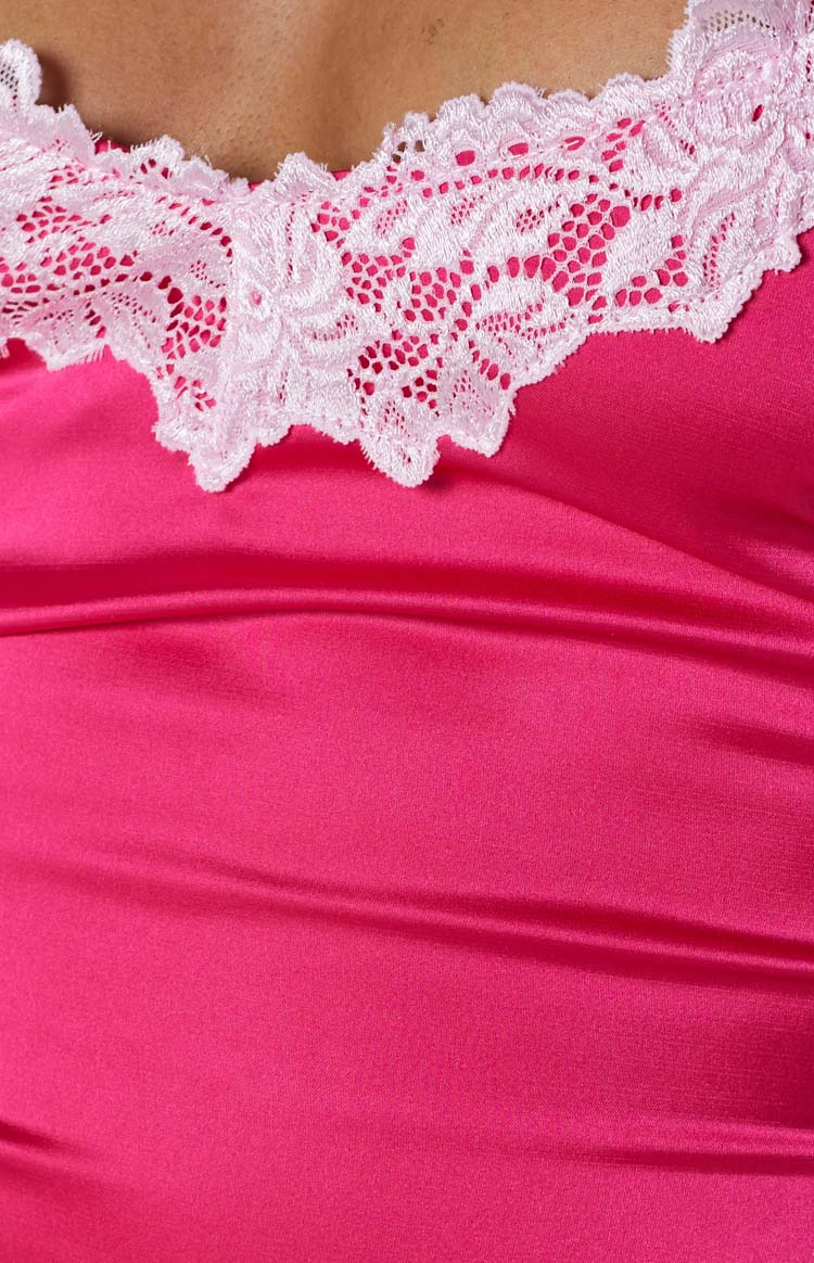 Close-up of the pink satin fabric with white scalloped lace trim along the neckline of the mini dress