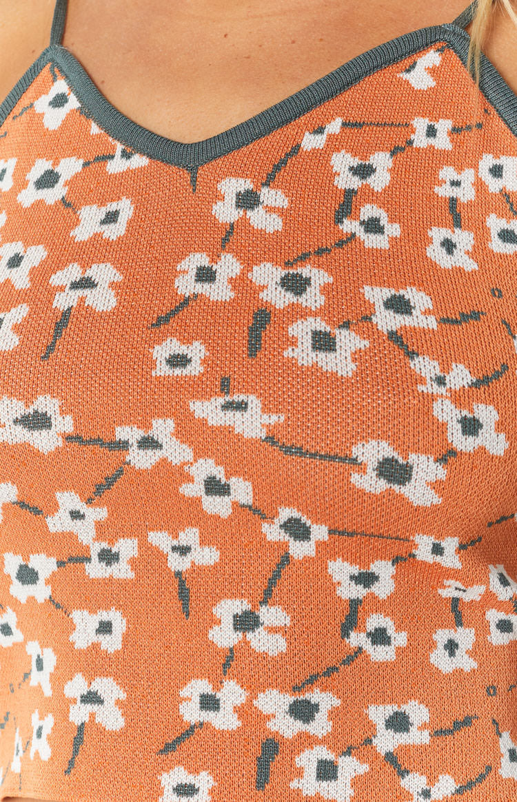 Orange knit crop top with white and grey blossom floral pattern and grey V-neck trim