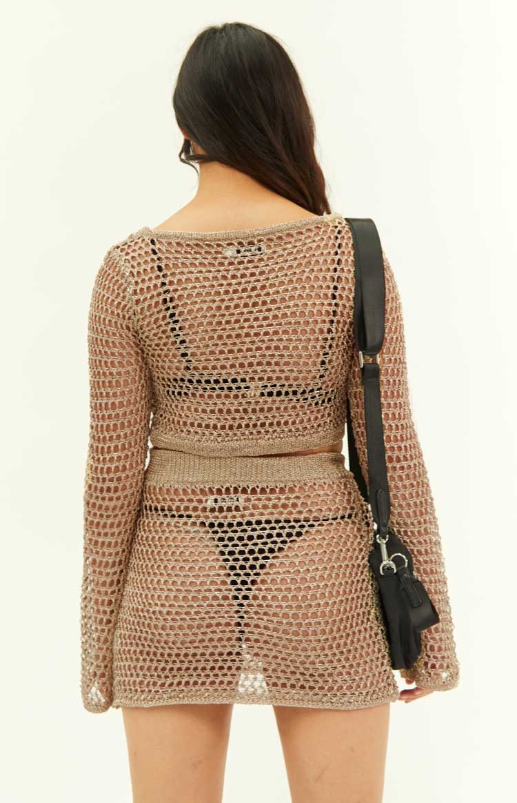 Rear view of a gold metallic fishnet mini skirt with a sheer knit texture