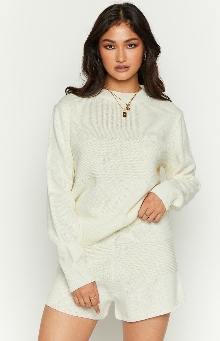 Cream long sleeve knit top with a high mock neck, ribbed cuffs, and horizontal textured knit panels
