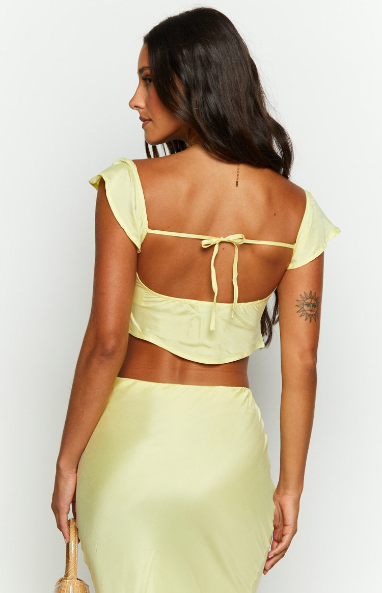 Back view of a yellow satin crop top featuring a low open back with a tie closure and short flutter sleeves