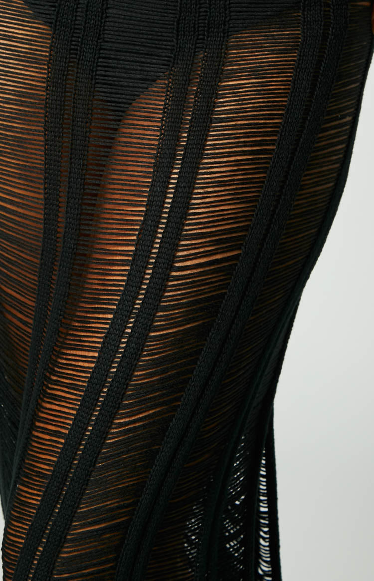 Close-up of the black ladder knit midi skirt fabric, showing sheer horizontal laddering and opaque vertical stripes