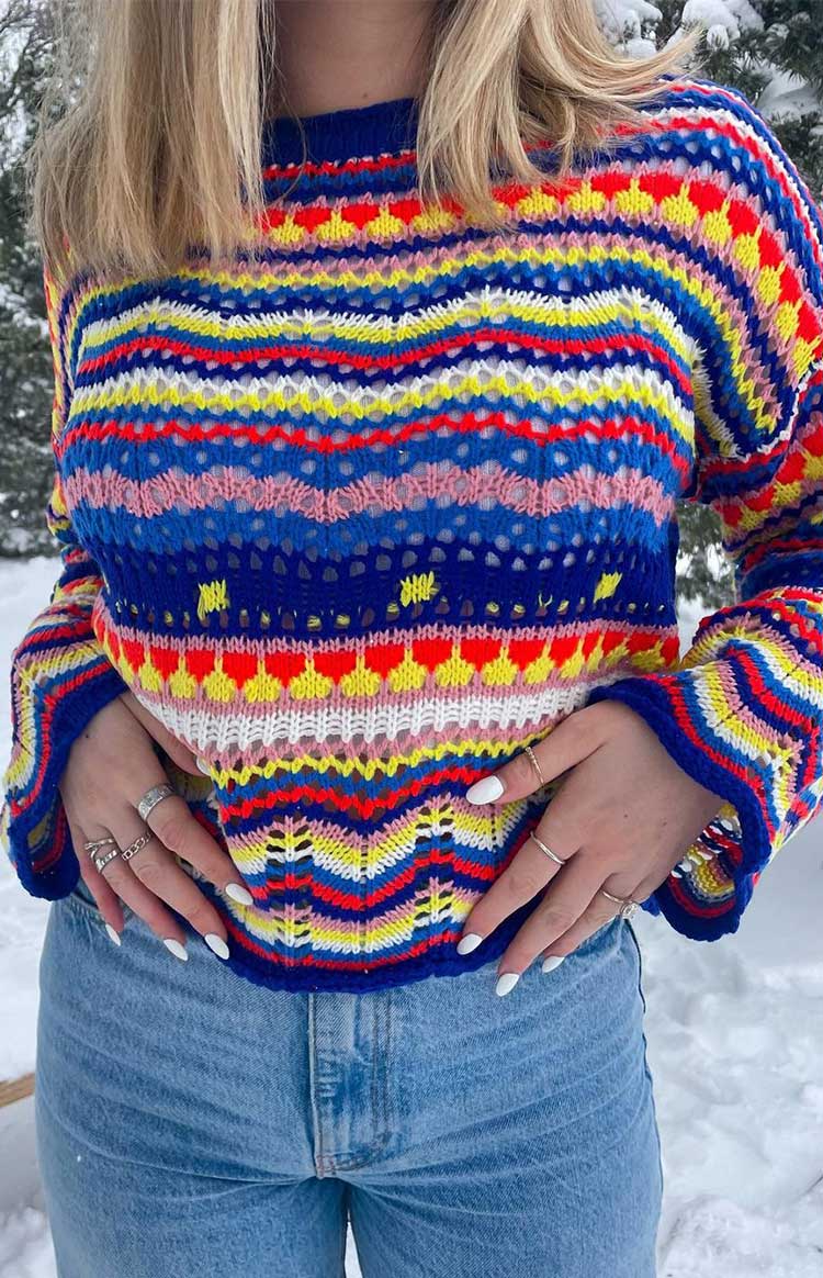 Vibrant crochet knit sweater with blue, red, yellow, pink, and white horizontal stripes, chevron patterns, high neck