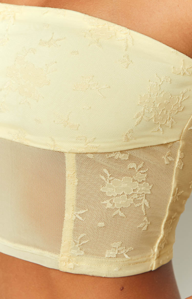 Close-up of the yellow mesh corset top showing floral lace detailing and a sheer plain mesh panel on the side